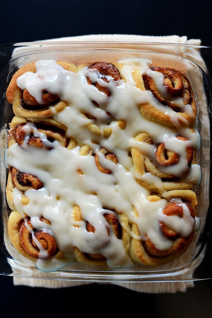 a casserole dish filled with cinnamon rolls covered in white sauce and icing