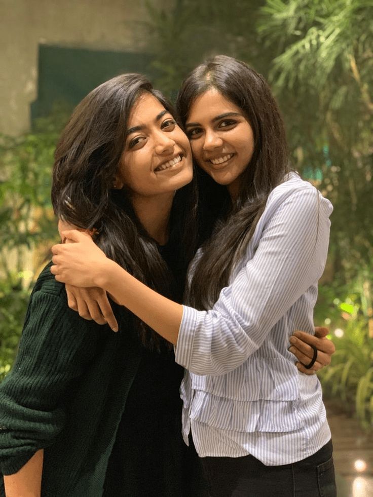 two women hugging each other in front of plants