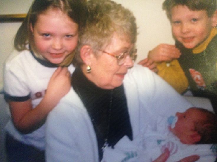 an older woman and two young children holding a baby