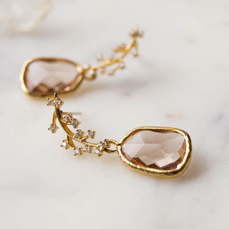 Our Juniper Branch Earrings are perfectly boho chic. They're simple, dainty and won't overpower your entire look on your special day! These also make a perfect gift for bridesmaids for a classic bohemian look.FEATURES Champagne hued glass drops set in 16k gold plating White cubic zirconia encrusted leaf post (925 sterling post) 100% nickel free, can be worn by people with sensitive ears Delicate Handmade Bridal Earrings, Elegant Gold Earrings For Bridesmaids, Gold Elegant Crystal Earrings For Bridesmaid, Handmade Rose Gold Elegant Bridal Earrings, Handmade Elegant Rose Gold Bridal Earrings, Feminine Bridal Drop Earrings As Gift, Feminine Bridal Drop Earrings For Gifts, Bohemian Crystal Drop Earrings For Wedding, Delicate Sterling Silver Earrings For Bridesmaids