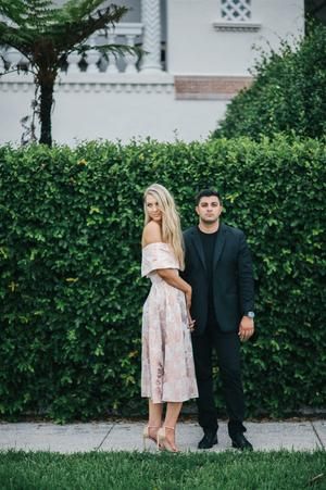 a man and woman standing in front of a hedge