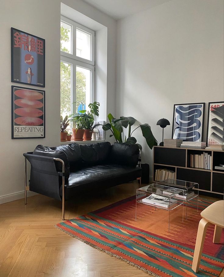 a black leather couch sitting in a living room next to a window