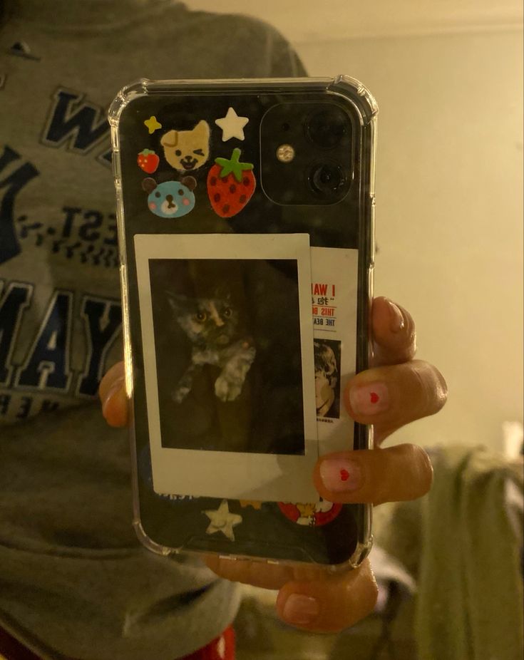 a person holding up a cell phone with pictures on the front and back of it