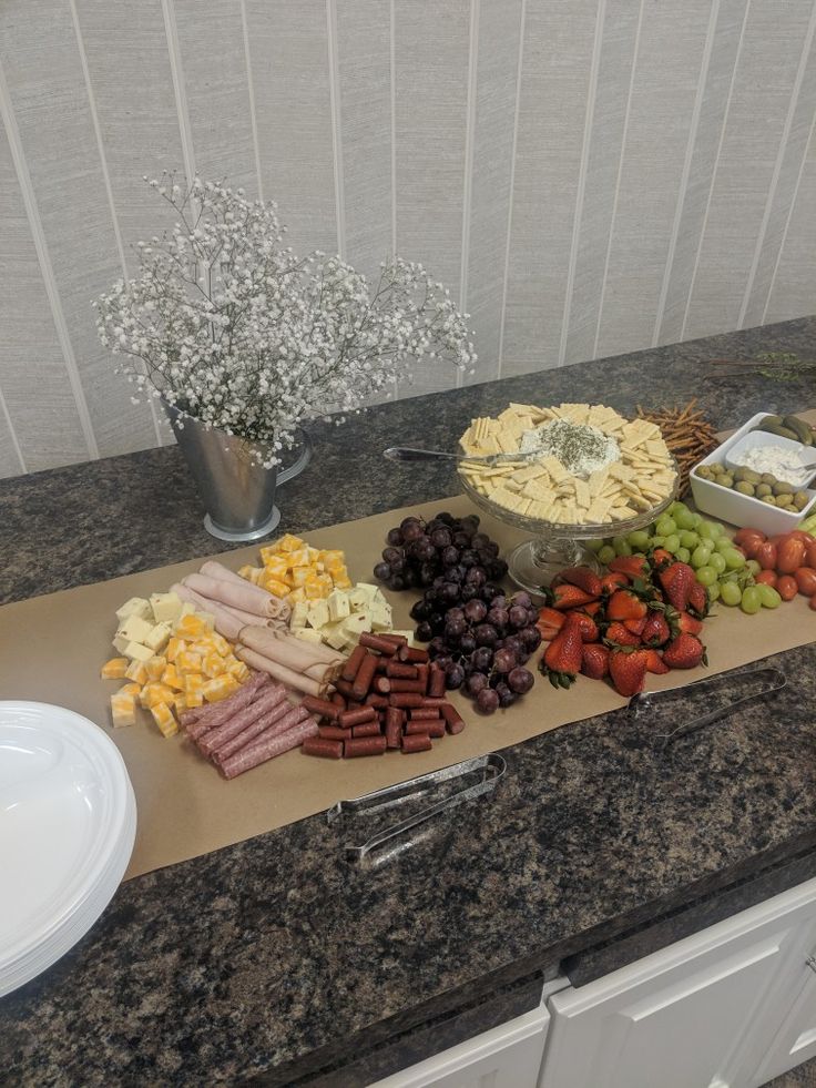 a table topped with lots of different types of cheese and crackers next to a vase filled with baby's breath