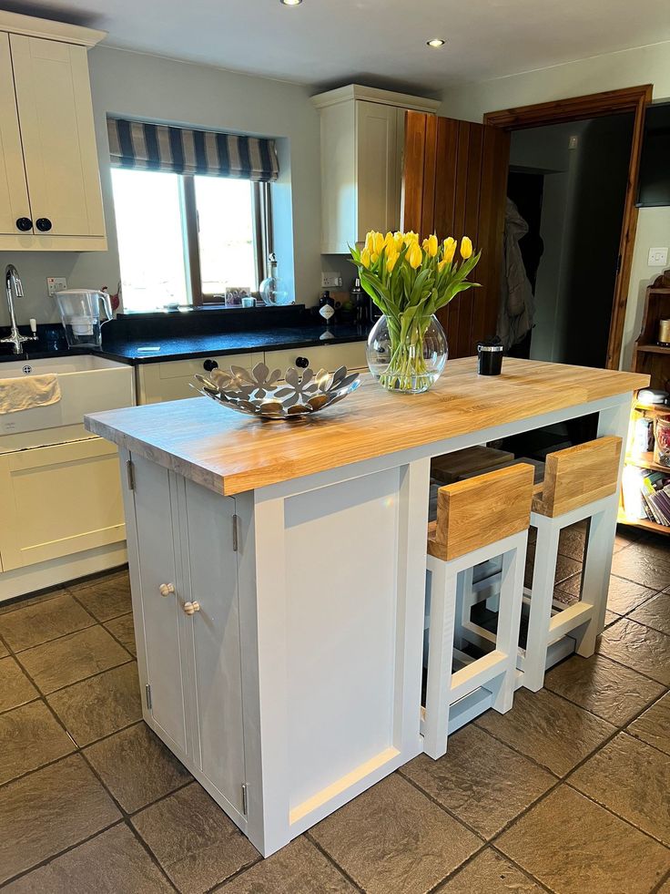 a kitchen with a center island in the middle of it and yellow flowers on top