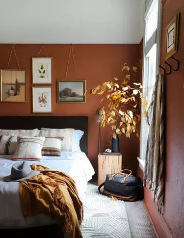 a bed sitting in a bedroom next to a mirror and a potted plant on top of a dresser