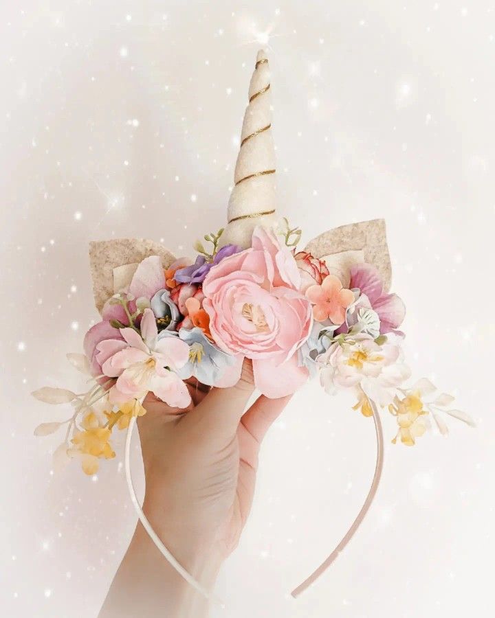 a hand holding a unicorn horn with flowers on it