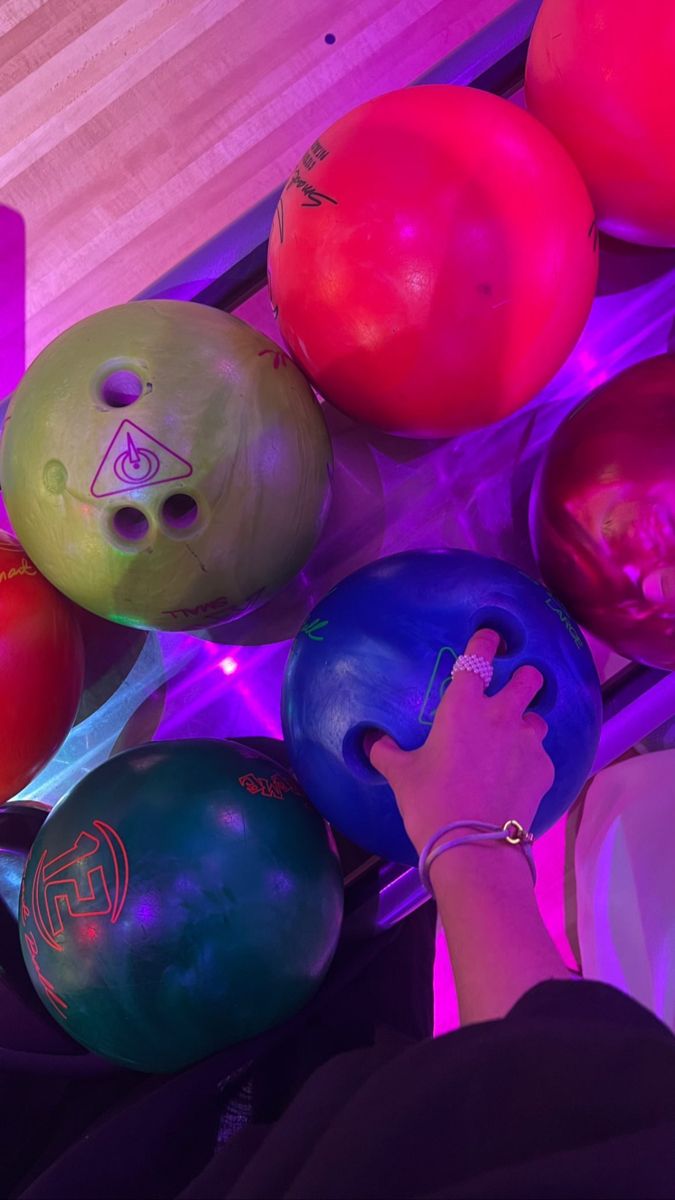 several bowling balls are being held up by a person's hand in front of them