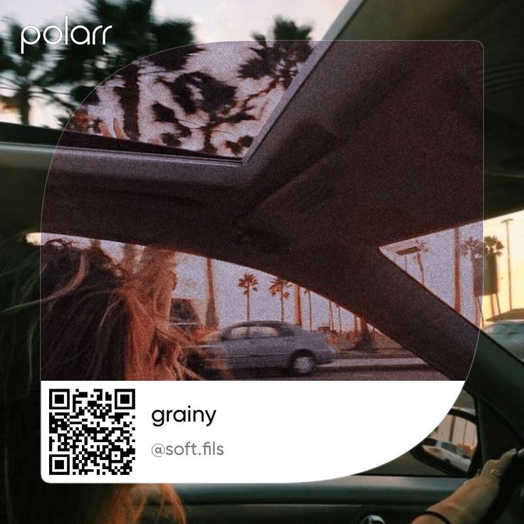 a woman driving down a street next to a palm tree covered road with qr code on the windshield