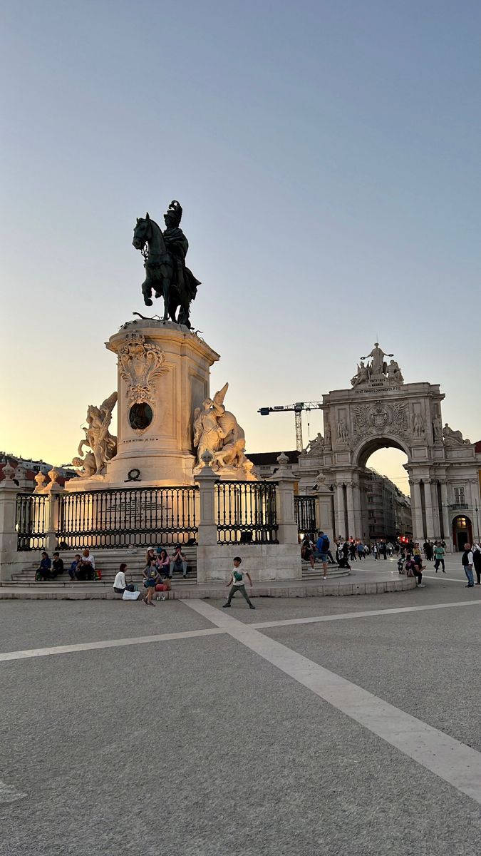 people sitting and walking around in front of a statue