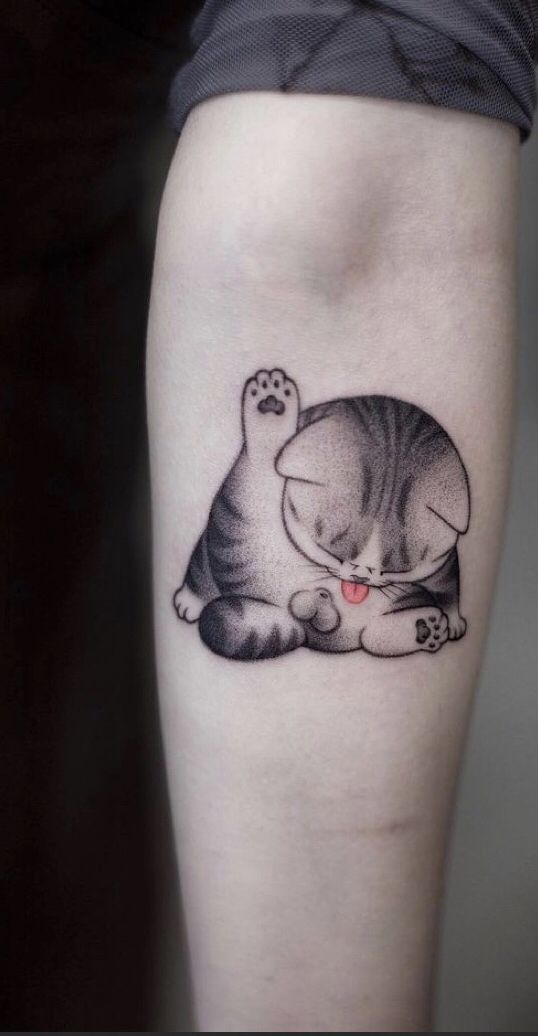 a cat laying down on top of a person's leg with its paw in the air