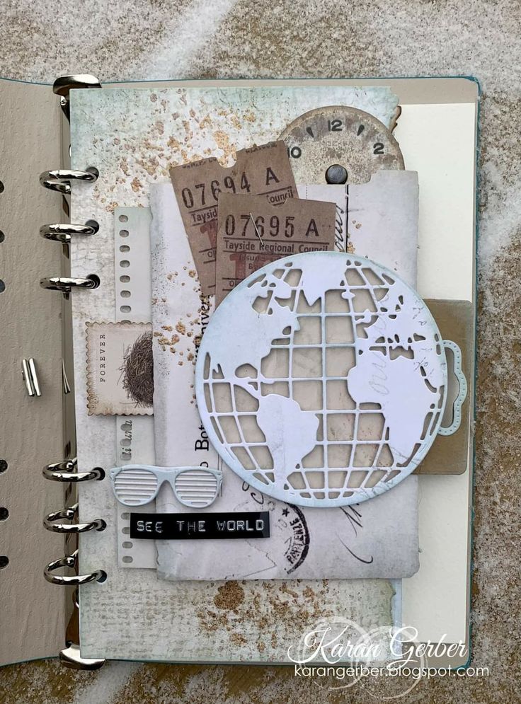 an open notebook with a world map on the cover and some other things in it