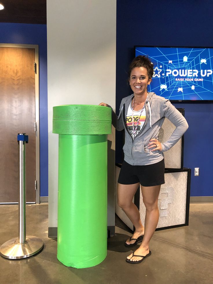 a woman standing next to a green trash can