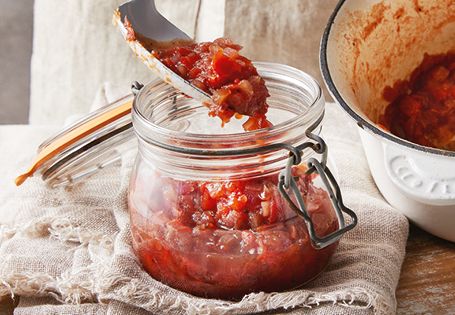 a spoon with some food in it next to a bowl filled with sauce and another dish