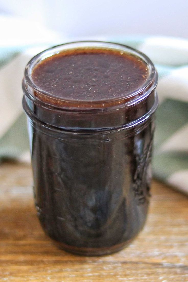 a jar filled with brown liquid sitting on top of a wooden table