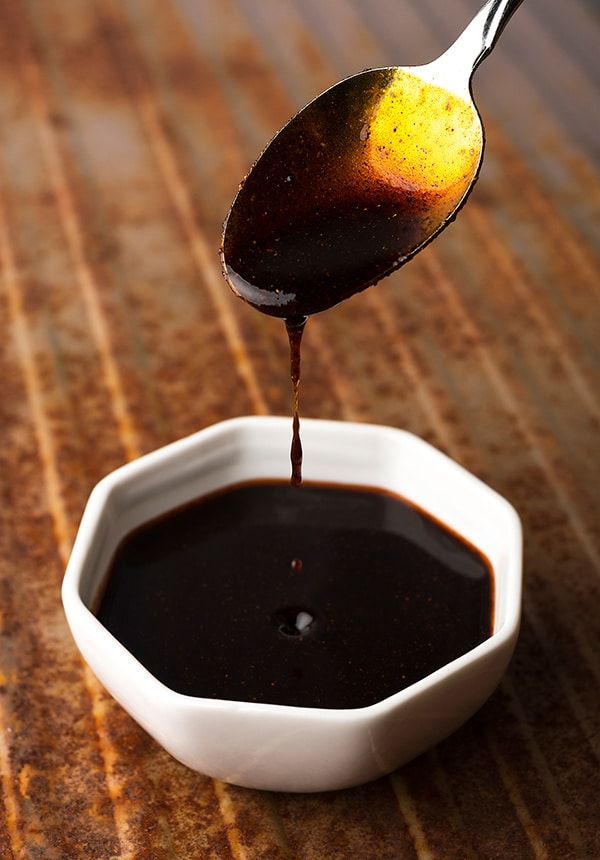 a spoon pouring sauce into a small white bowl