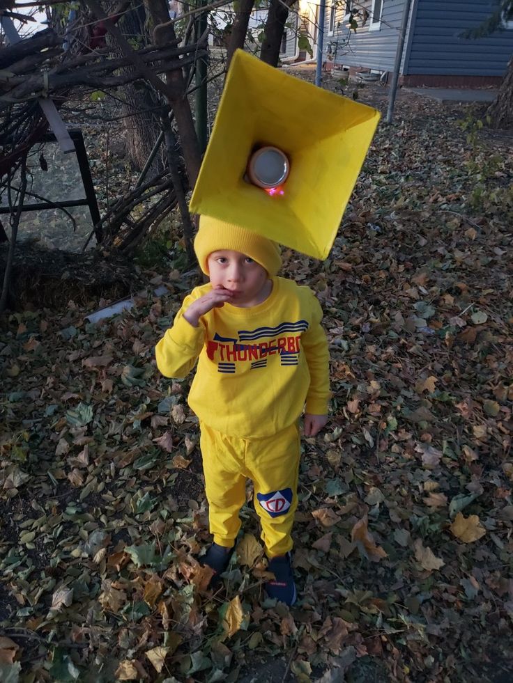 a little boy in a yellow costume with a box on his head