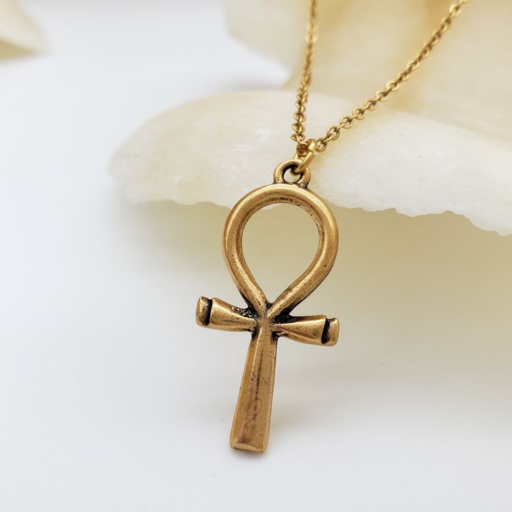 The Egyptian Ankh symbolizes life, protection & eternity. Its power was believed to protect the dead and ensure eternal life. Wear a piece of Ankh jewelry for protection, a reminder of the past, or just as an accessory. Materials: 1” pewter charm with 18" gold plated brass chain Made in USA Symbolic Engraved Ankh Jewelry, Egyptian Writing, Ankh Jewelry, Gold Ankh Brass Jewelry, Bronze Ankh Necklace, Vintage Ankh Metal Necklace, Unique Ankh-shaped Brass Jewelry, Ankh Pendant, Egyptian Ankh