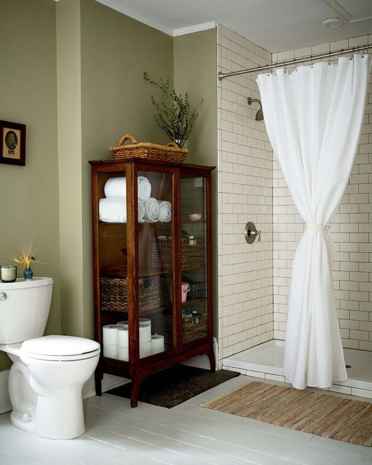 a white toilet sitting next to a wooden cabinet in a bathroom under a shower curtain