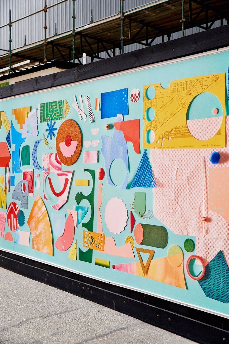 a man riding a skateboard next to a wall covered in colorful art on the side of a building