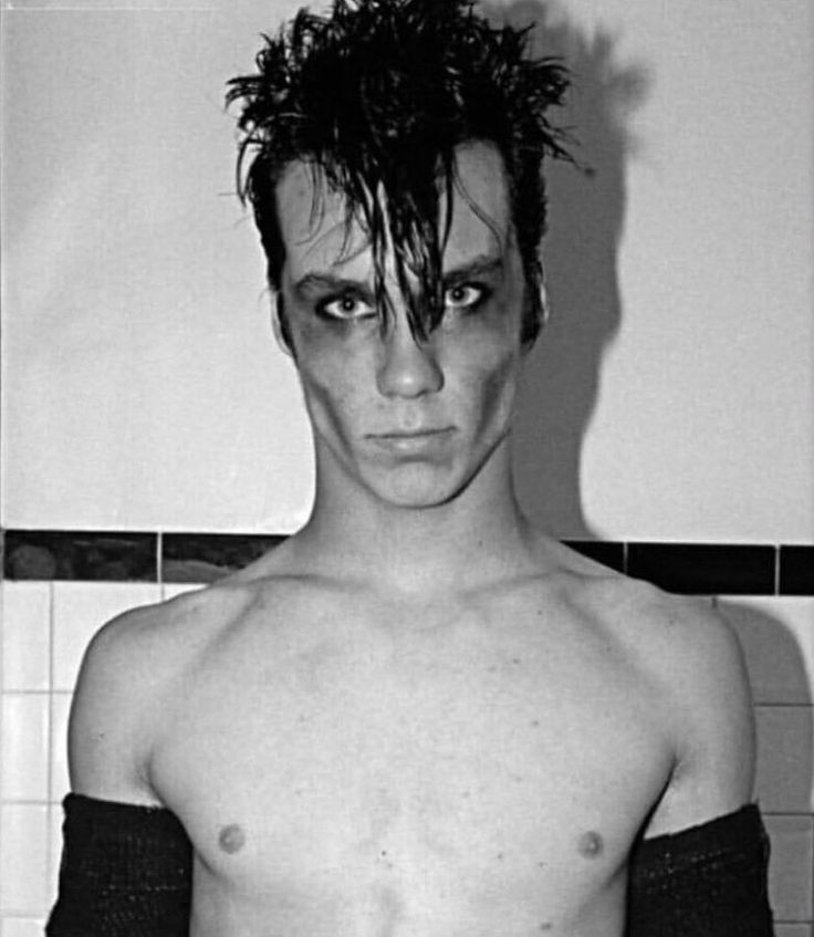 black and white photograph of a shirtless man in the bathroom with his hair pulled back