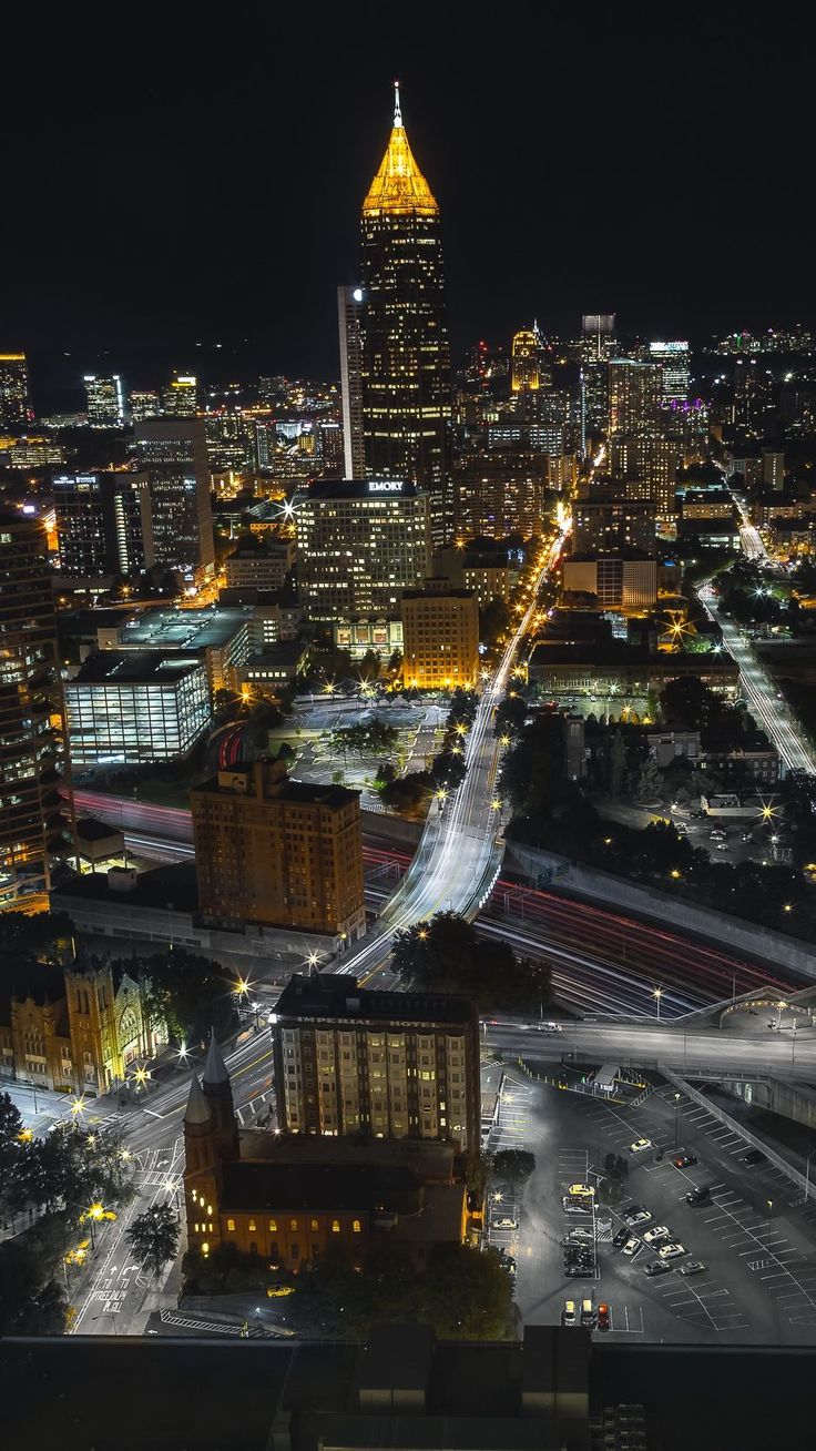 an aerial view of a city at night with lights and buildings in the foreground