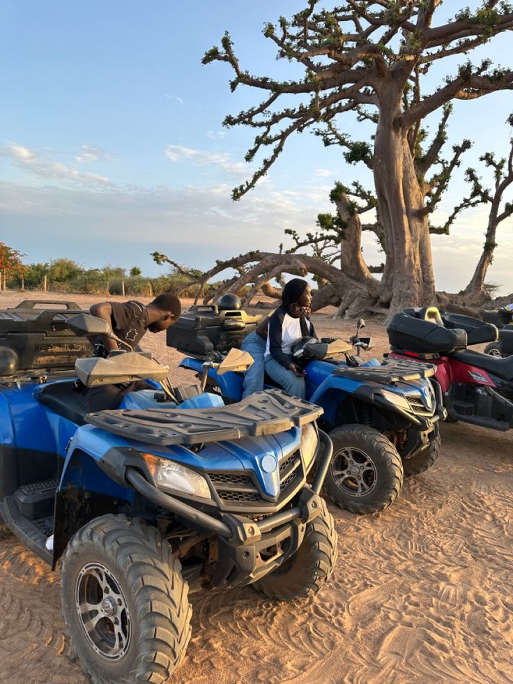 two people riding four wheelers in the sand