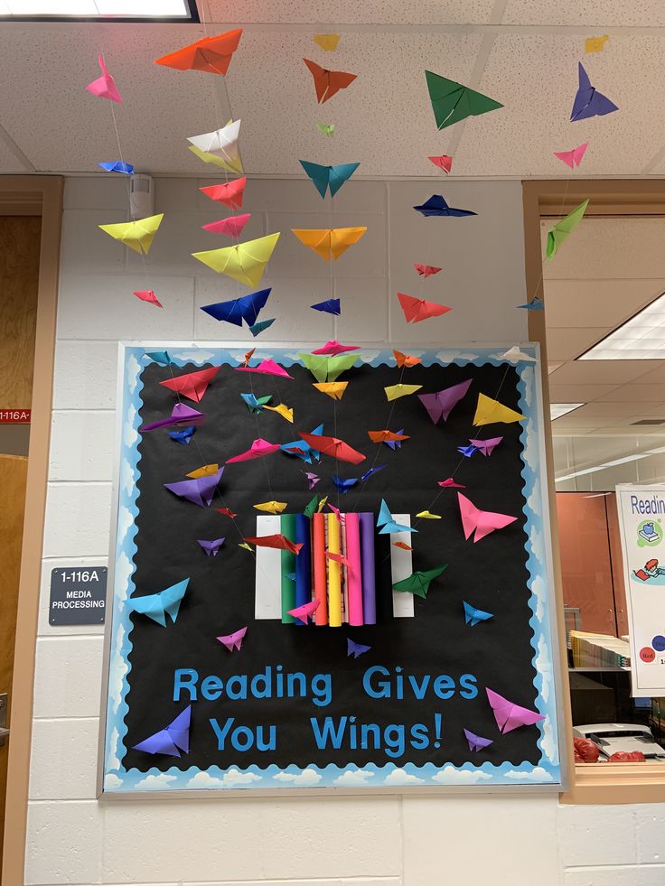 a bulletin board with colorful origami birds and reading gives you wings