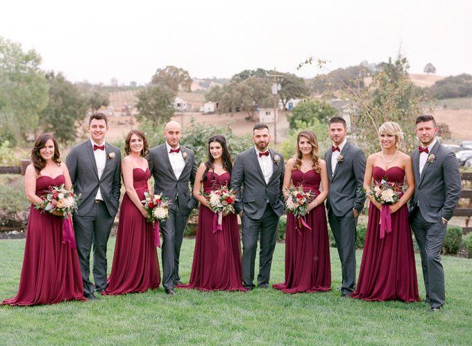 a group of people in formal wear posing for a photo on the grass with flowers