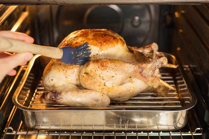 a person cleaning a chicken in an oven with a brush on it's head