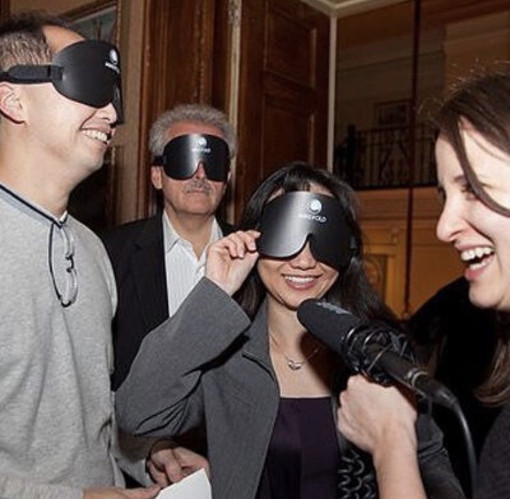 three people wearing blindfolds and smiling at each other