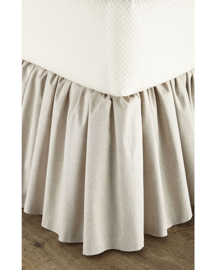 the bottom of a bed with pleated bedskirt