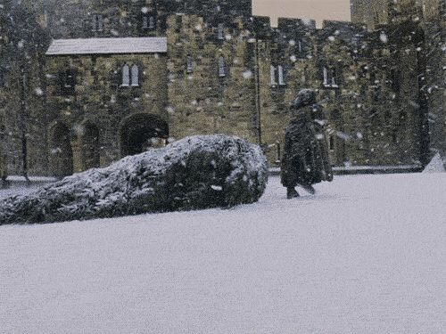 a person walking in the snow near a castle