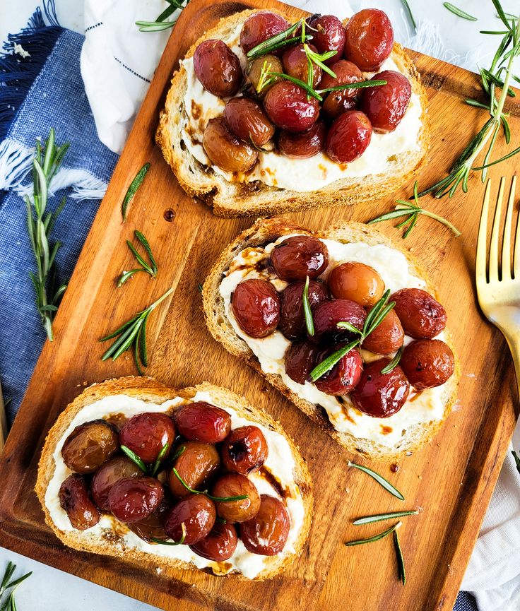 three pieces of bread with olives and goat cheese on them, sitting on a cutting board