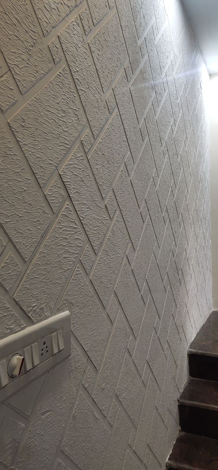 a white toilet sitting next to a set of stairs in a bathroom under a light fixture