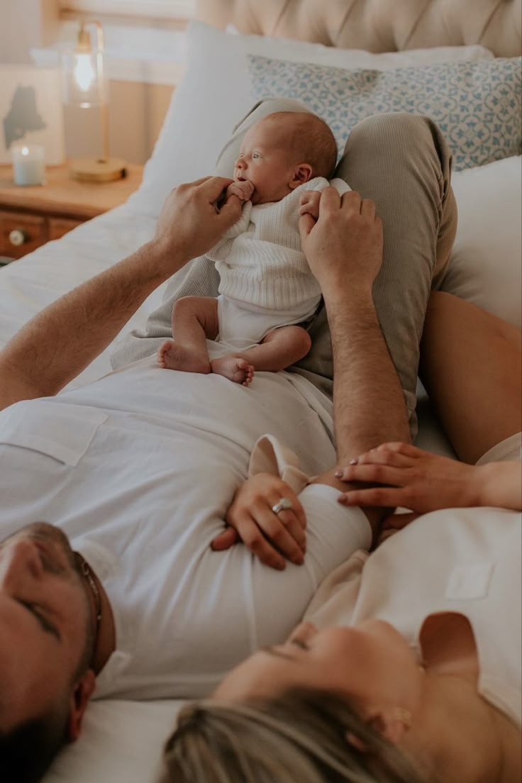 a man and woman laying on top of a bed holding a baby