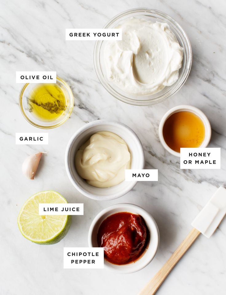 ingredients for homemade mayonnaise laid out on a white marble counter top with names