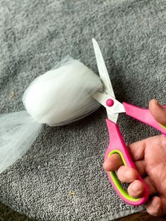 a person holding a pair of scissors in front of a piece of cloth and garlic