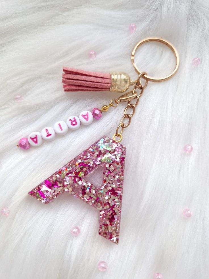 a pink and white keychain with the letter a on it