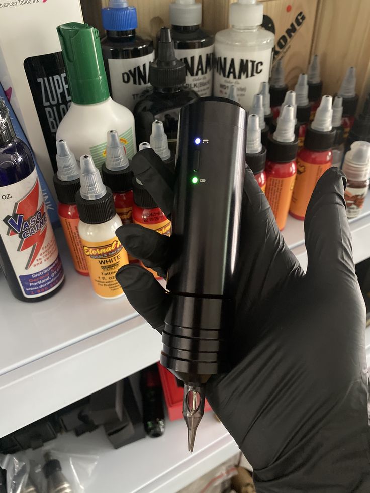 a person holding a pen in their hand with bottles on the shelf behind them and an assortment of other items