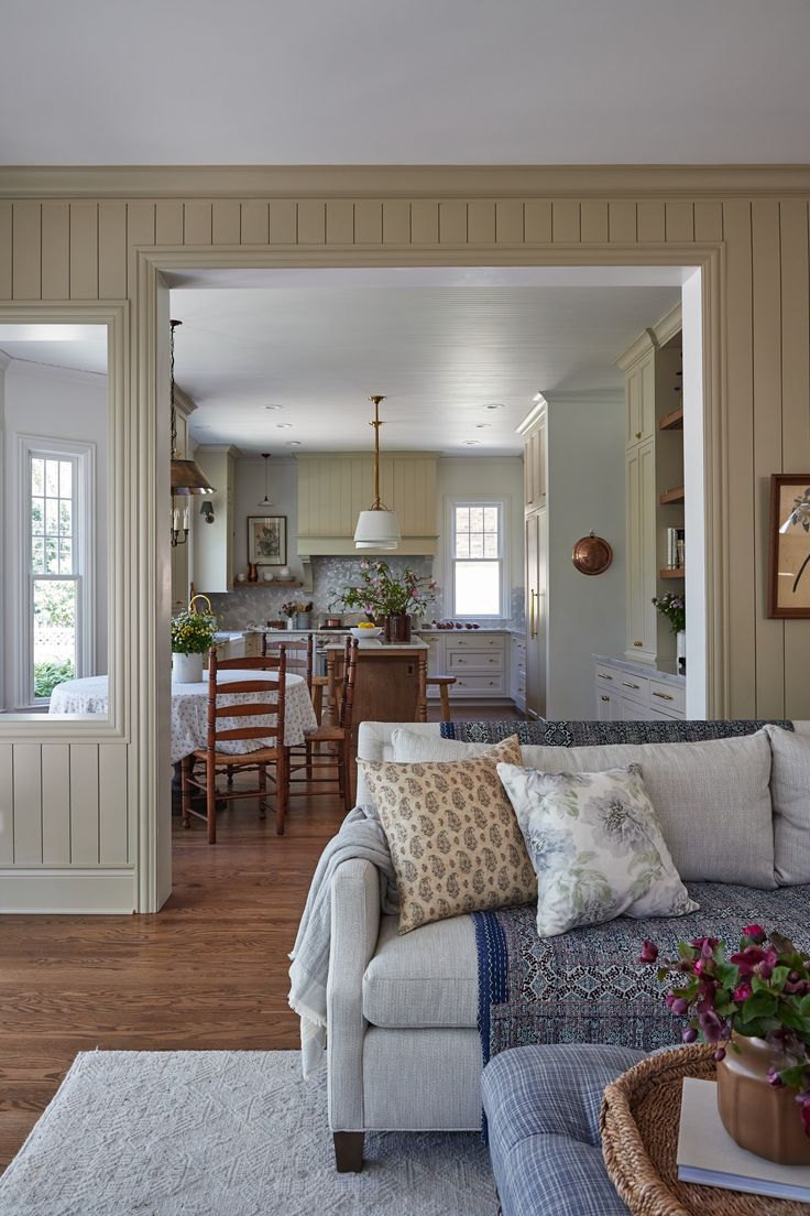 a living room filled with furniture next to a dining room table and kitchen in the background