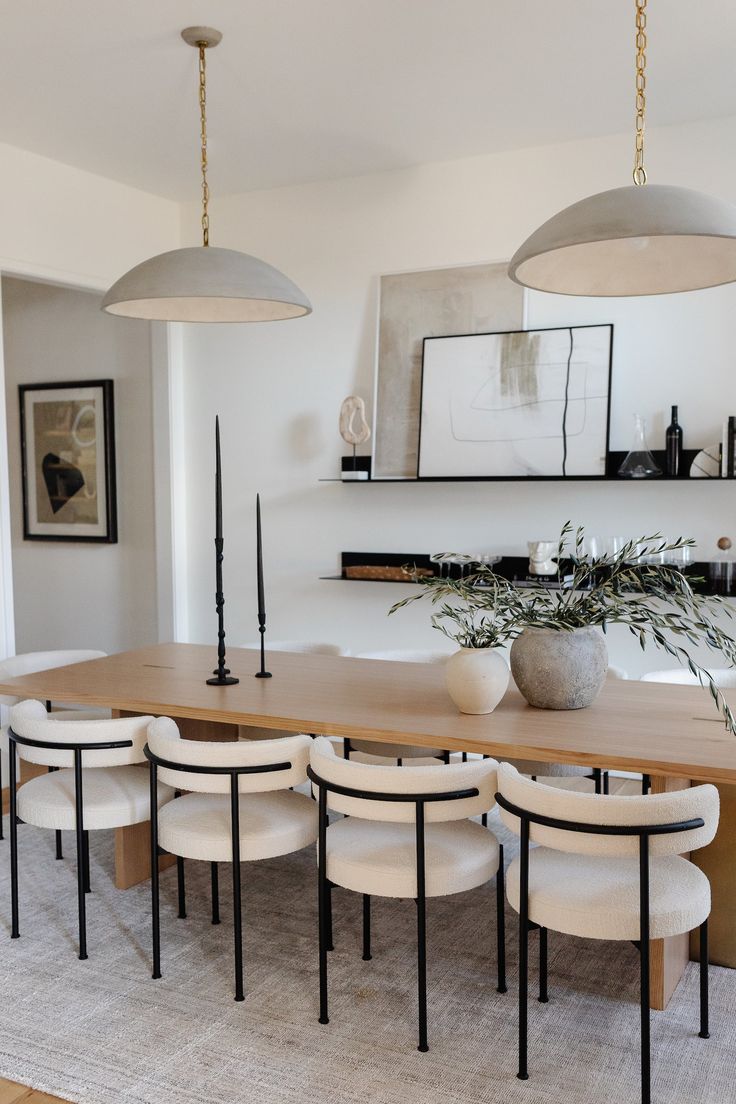 a dining room table and chairs with plants in the vases on each one side