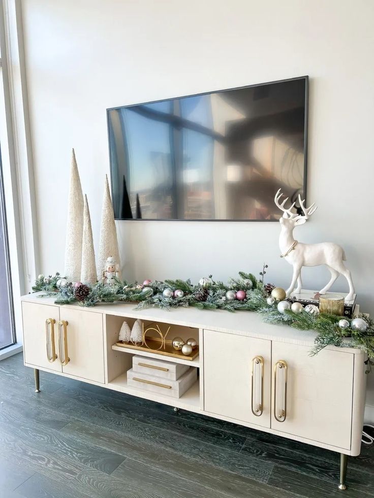 a christmas mantel with ornaments and deer figurines in front of a large painting