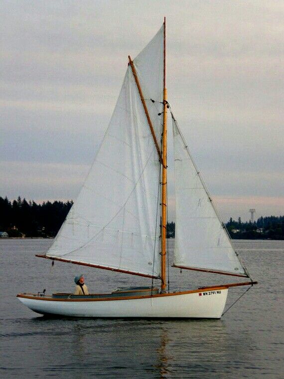 a sailboat with white sails is in the water on a cloudy day at dusk