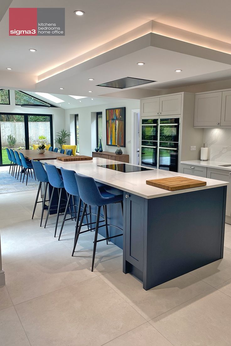 a large kitchen with blue chairs and an island in the middle, is shown from across the room