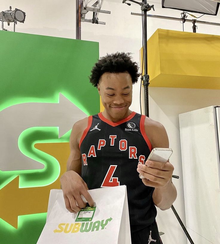 a young man holding a smart phone and shopping bags