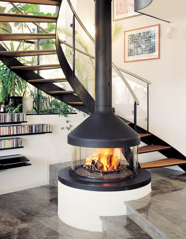 a fire place sitting in the middle of a living room next to a stair case