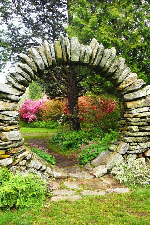 a stone arch in the middle of a garden