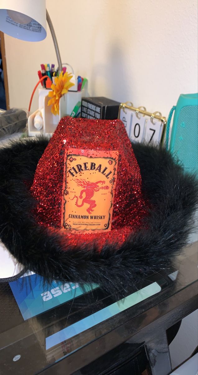 a red hat sitting on top of a desk next to a lamp and other items