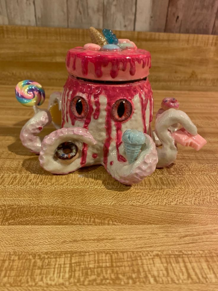 a pink and white ceramic container with an octopus on it's side, sitting on a wooden surface